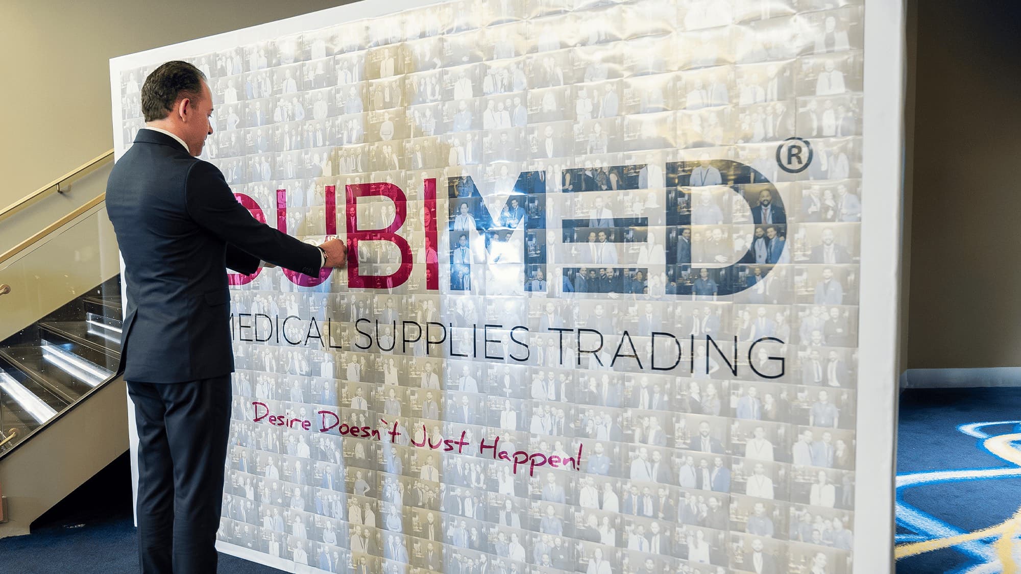 Safi Rajab at the DUBIMED photo wall, built from hundreds of team and partner portraits